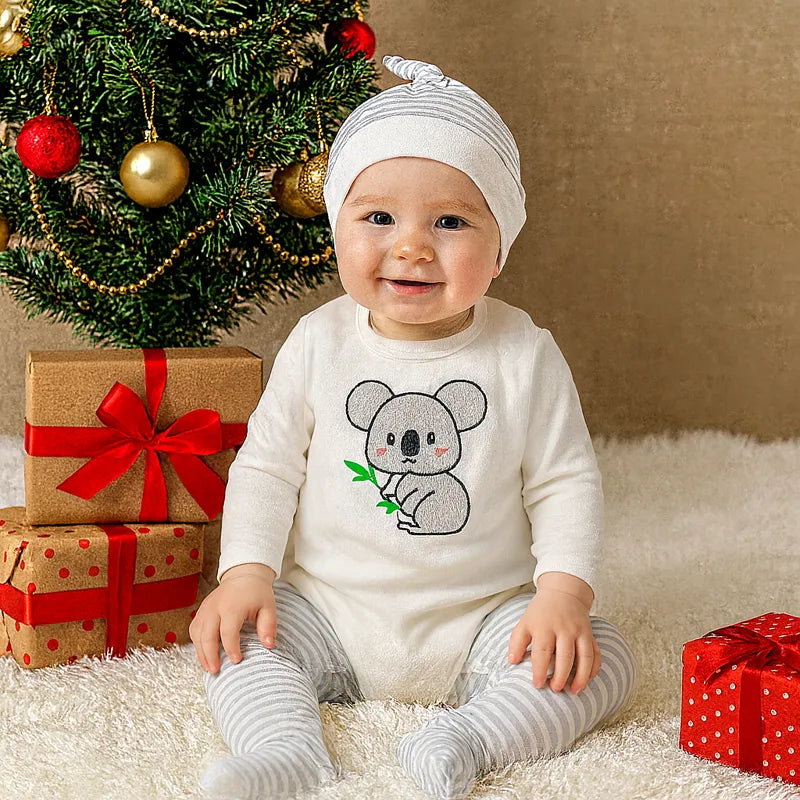 Bébé garçon souriant en pyjama koala près du sapin de Noël