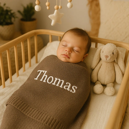 Bébé garçon endormi emmailloté dans une couverture personnalisée brune au prénom Thomas