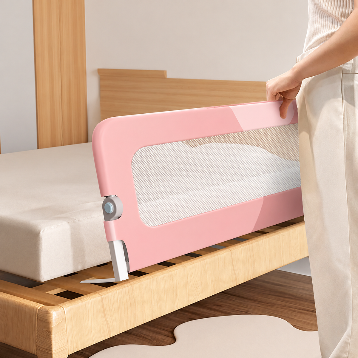 Installation d’une barrière de lit rose avec filet blanc sur un lit en bois.