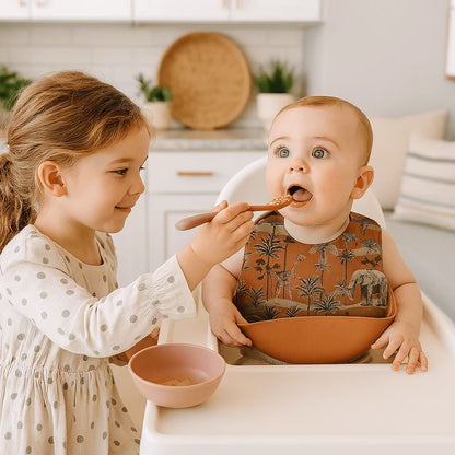 Bébé nourri avec un bavoir bébé en silicone marron illustré de girafes et d’éléphants