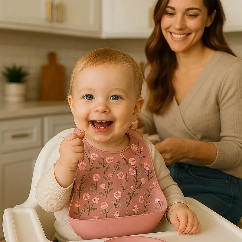 Bébé souriant portant un bavoir bébé en silicone rose décoré de fleurs