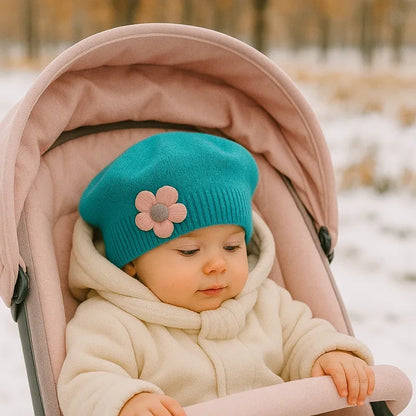 Bébé emmitouflé dans une poussette, portant un béret bleu turquoise avec fleur décorative
