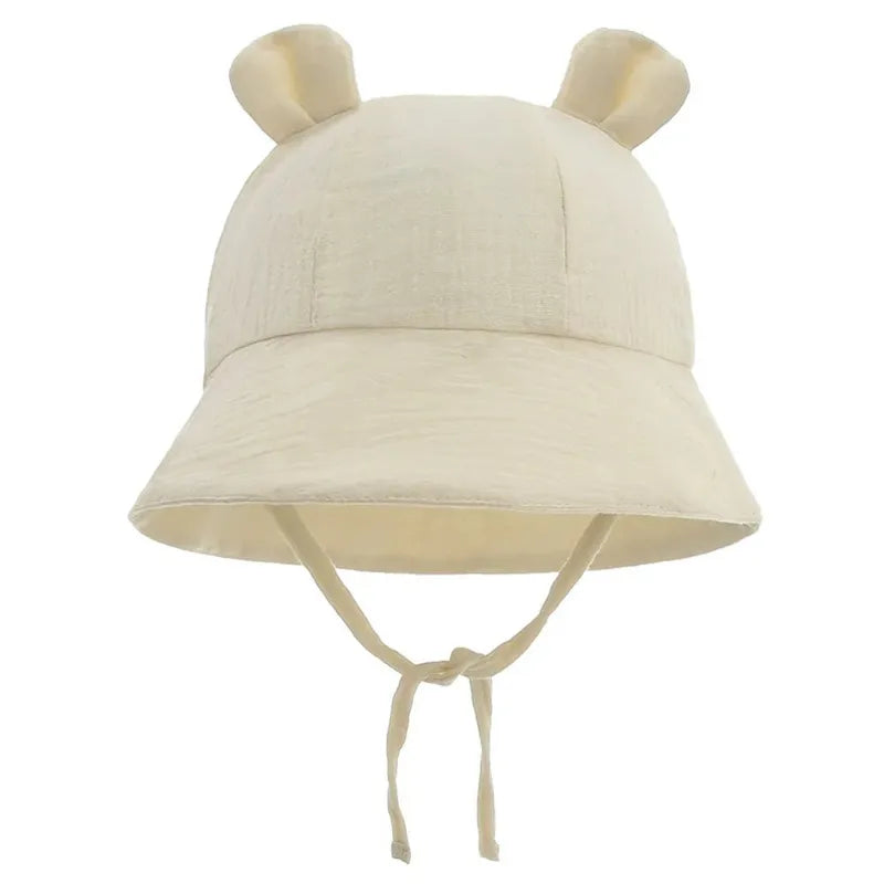 Chapeau bébé uni en mousseline beige clair avec petites oreilles.