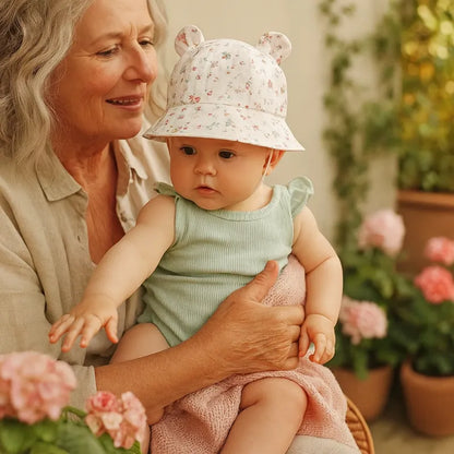 Bébé avec chapeau à fleurs roses sur les genoux de sa grand-maman.