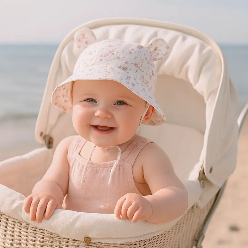Bébé souriant avec chapeau fleuri dans une poussette au bord de mer.