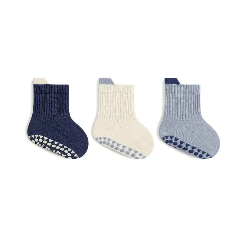 Chaussettes bébé bleues et crème antidérapantes en coton respirant, idéales pour garder les petits pieds au chaud.