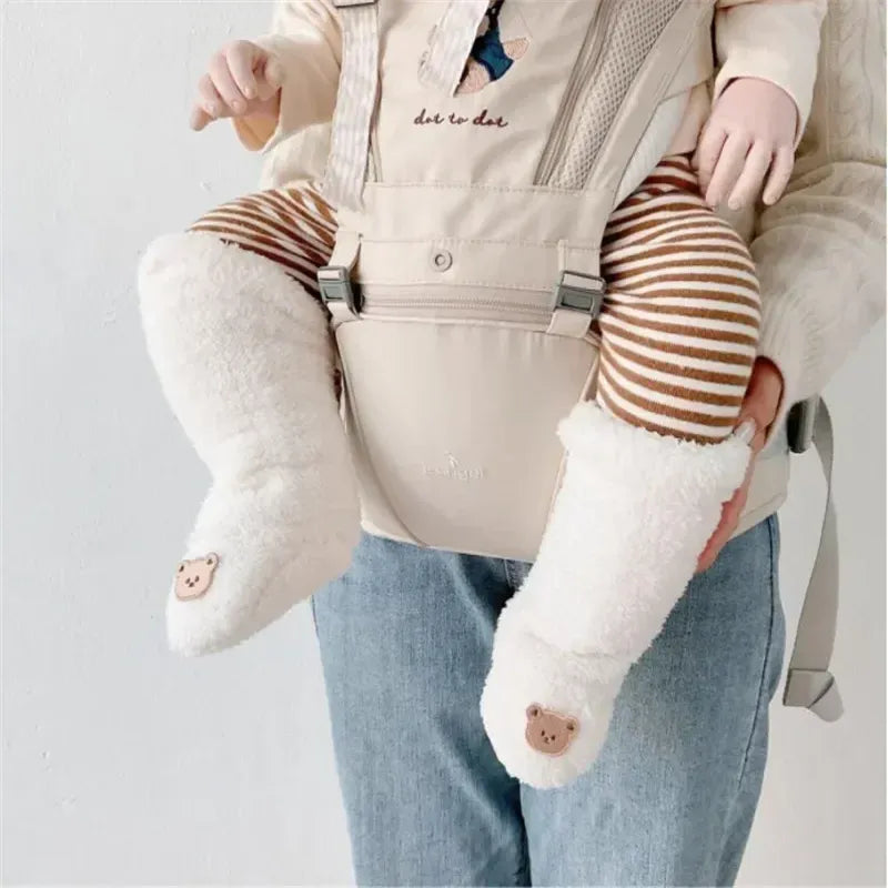 Bébé porté en porte-bébé portant des chaussettes bébé chaudes blanches en peluche avec motif ourson.