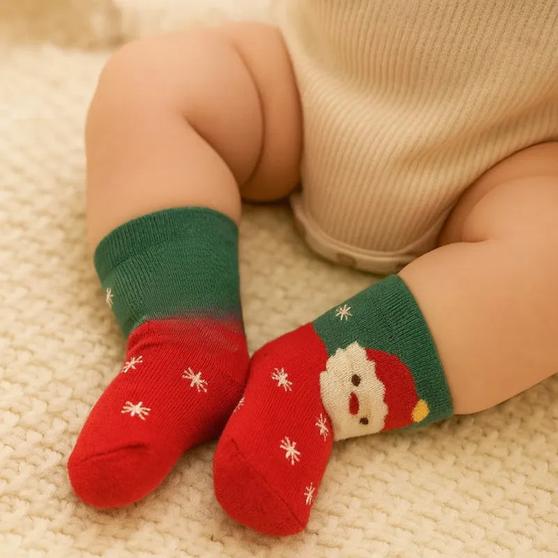 Chaussettes bébé Noël rouges et vertes portées par un bébé assis”