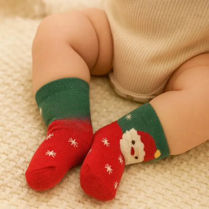Chaussettes bébé Noël rouges et vertes portées par un bébé assis”