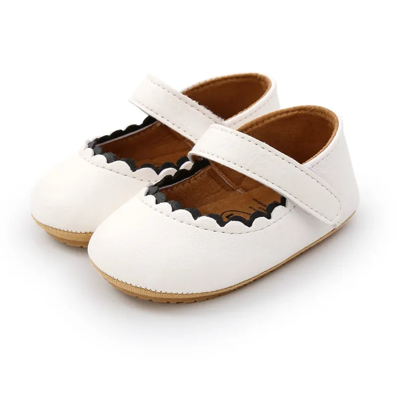 Chaussures bébé blanches en cuir souple avec semelle antidérapante, idéales pour les premiers pas.