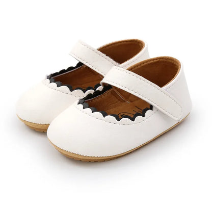 Chaussures bébé blanches en cuir souple avec semelle antidérapante, idéales pour les premiers pas.