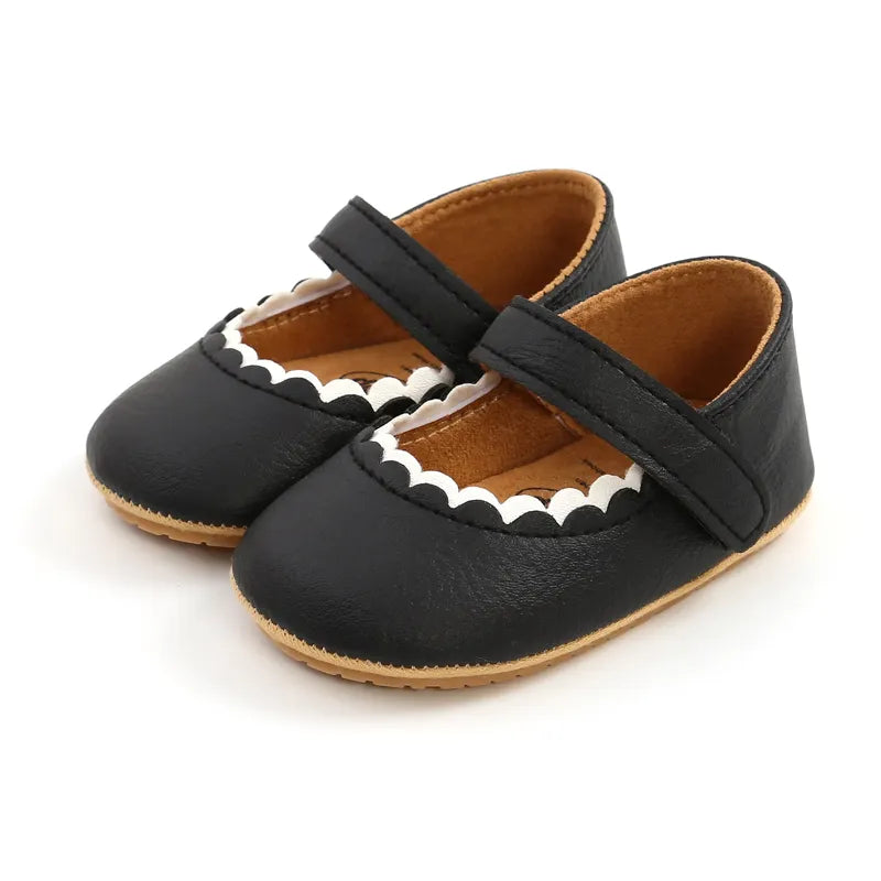Chaussures bébé noires élégantes en cuir avec semelle antidérapante, adaptées pour les premiers pas.