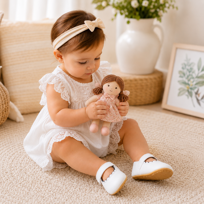 Bébé jouant avec une poupée et portant des chaussures souples blanches