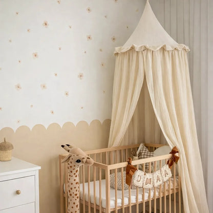Ciel de lit bébé crème style nordique au-dessus d’un lit bébé en bois dans une chambre bébé