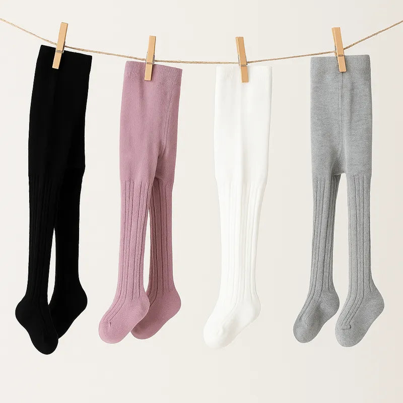 Collants bébé doux suspendus sur corde à linge tons pastel noir rose blanc gris