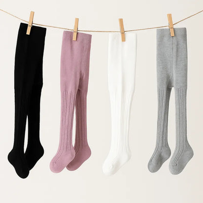 Collants bébé doux suspendus sur corde à linge tons pastel noir rose blanc gris