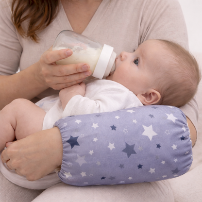 Maman qui donne le biberon a son bébé sur coussin avec étoiles