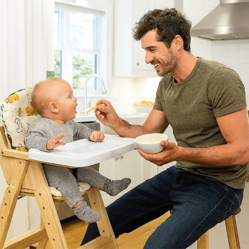 Papa nourrit bébé assis sur chaise haute avec coussin confortable
