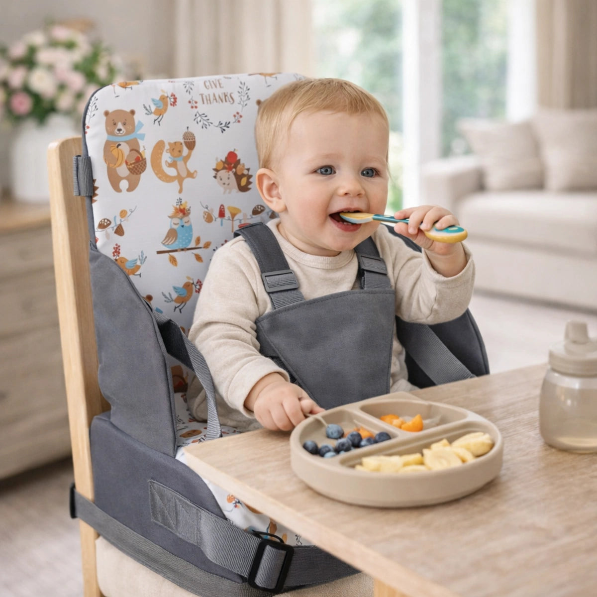 coussin rehausseur enfant installé sur chaise avec bébé mangeant seul à table avec assiette