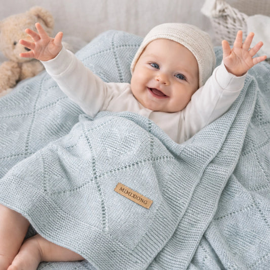 Bébé allongé sur le sol avec une couverture bébé en tricot bleu clair,