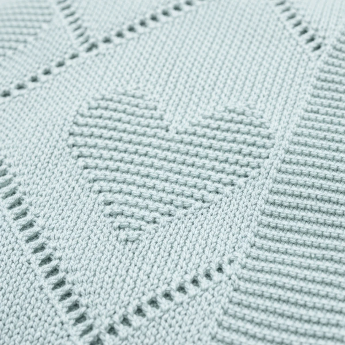 Gros plan sur le tricot d’une couverture bébé verte avec motifs cœur,
