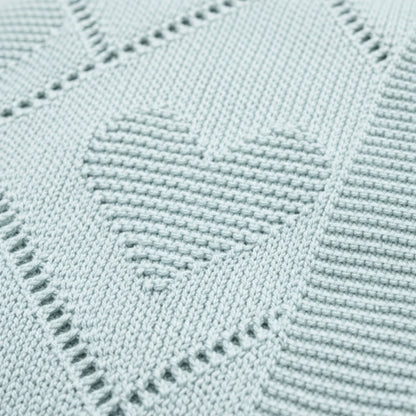Gros plan sur le tricot d’une couverture bébé verte avec motifs cœur,