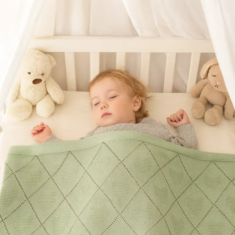 Enfant endormi sous couverture bébé tricot coton verte motif cœur