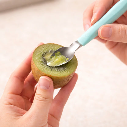 Gros plan cuillère fruit bébé dentelée découpant kiwi frais, cuillère bébé ergonomique