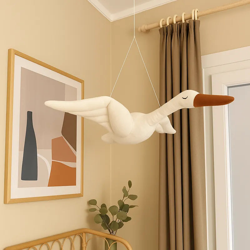 Décoration murale cygne en peluche suspendue dans une chambre bébé beige, ambiance douce et scandinave.