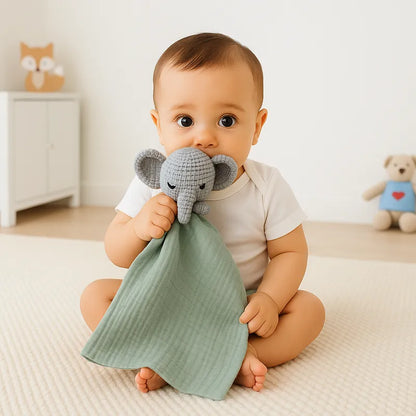 Bébé assis joue avec un doudou éléphant gris et tissu vert