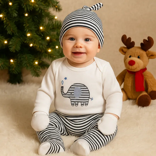 Bébé garçon en tenue éléphant rayée posant devant le sapin de Noël