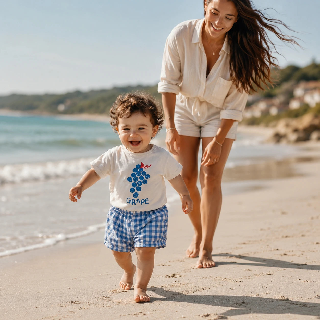  Bébé portant un ensemble bleu à carreaux avec maman sur la plage en été.