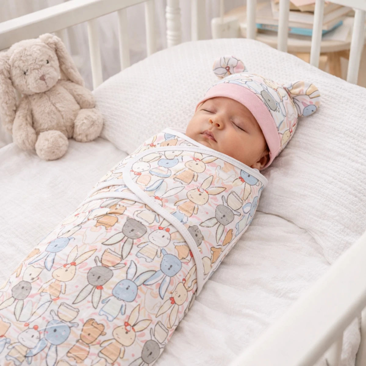 Gigoteuse bébé 0-6 mois en coton doux, motif lapins roses, bébé dormant paisiblement dans un lit bébé, décoration naturelle.