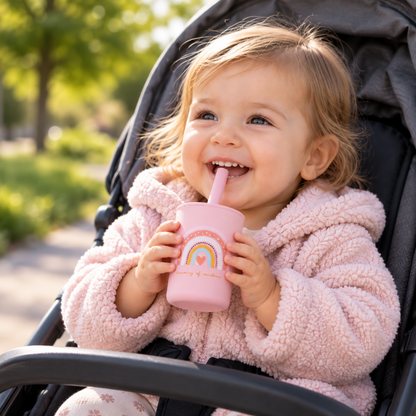 Bébé en poussette buvant avec un gobelet à paille rose