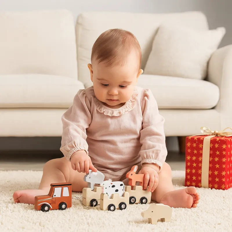 Bébé fille souriante tirant un train en bois pastel dans une chambre décorée beige et naturelle.