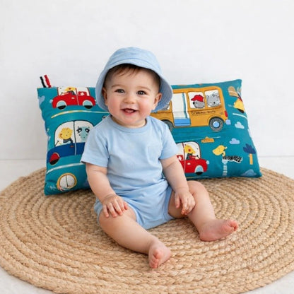 Bébé assis souriant avec oreiller bébé bleu motif voiture pour soutien de la tête et confort