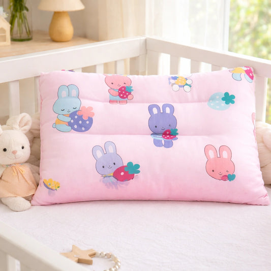 Oreiller bébé rose à motif lapins, posé dans une couchette blanche