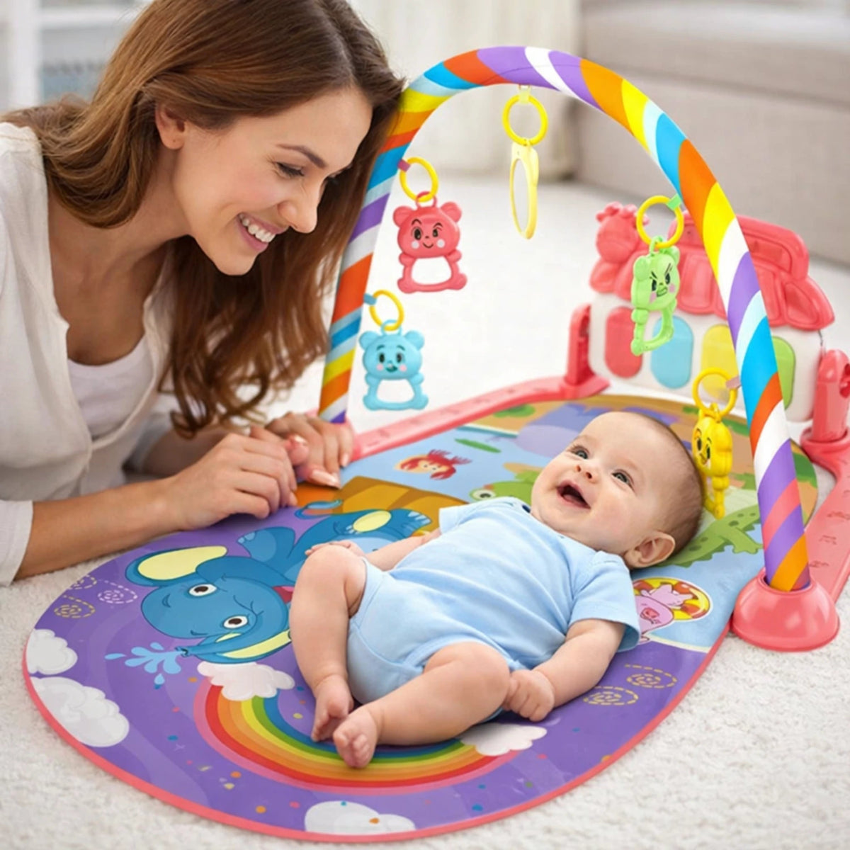 Tapis d’éveil musical bébé avec arche arc-en-ciel et maman souriante regardant son enfant