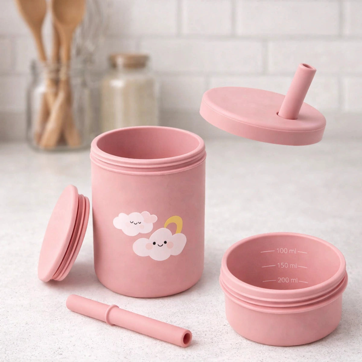 Tasse bébé silicone rose avec paille démontée, éléments vue éclatée sur comptoir de cuisine