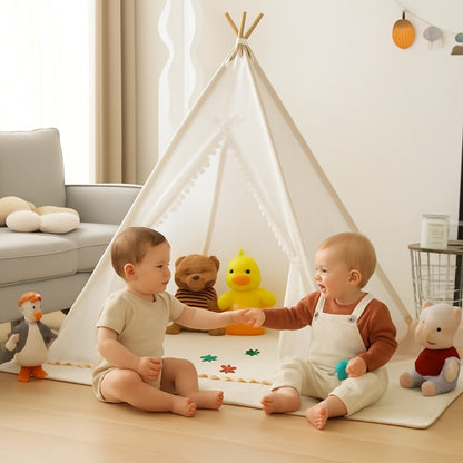 Deux bébés jouent ensemble devant un tipi blanc décoré de guirlandes lumineuses