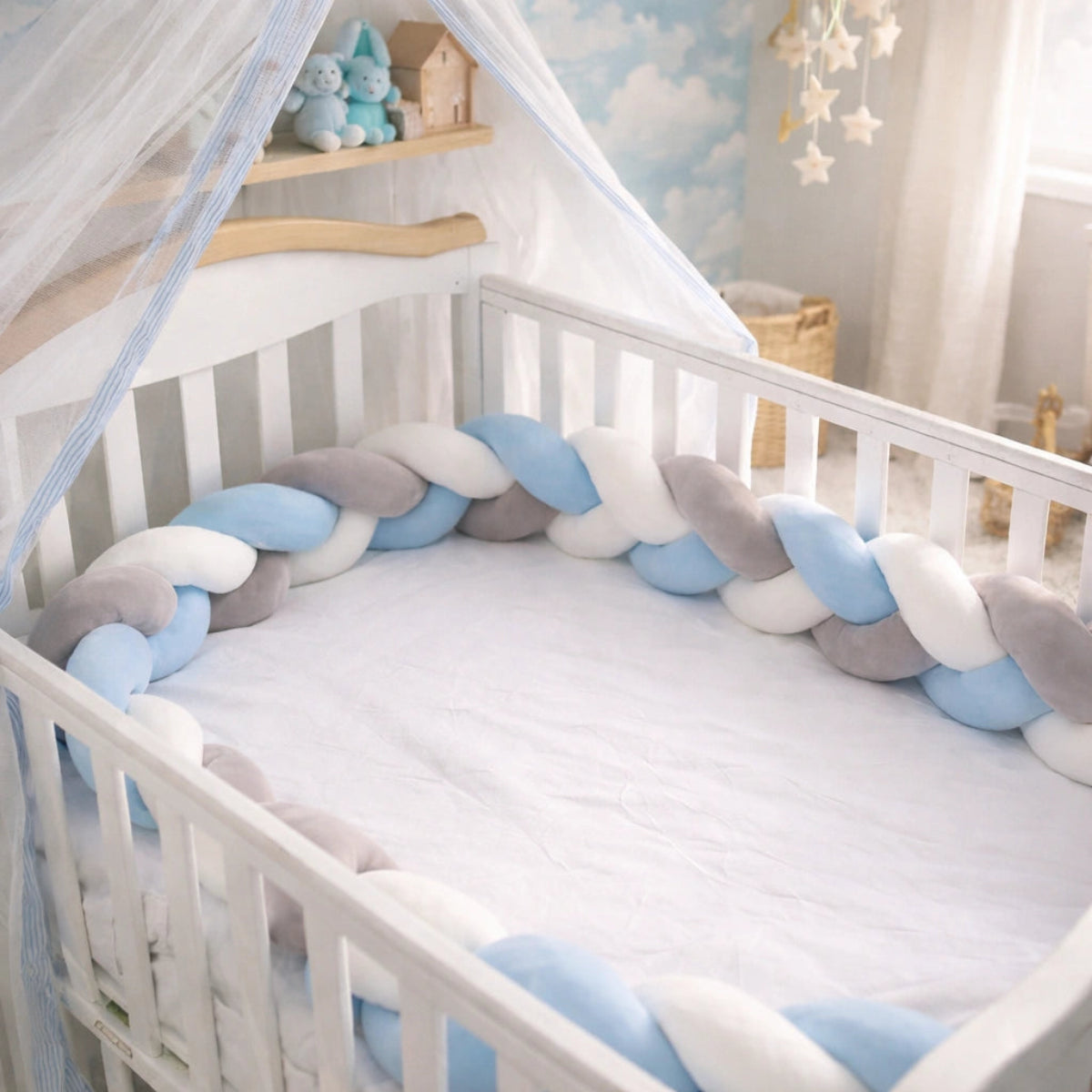 Tour de lit bébé tressé bleu, gris et blanc installé dans un lit bébé