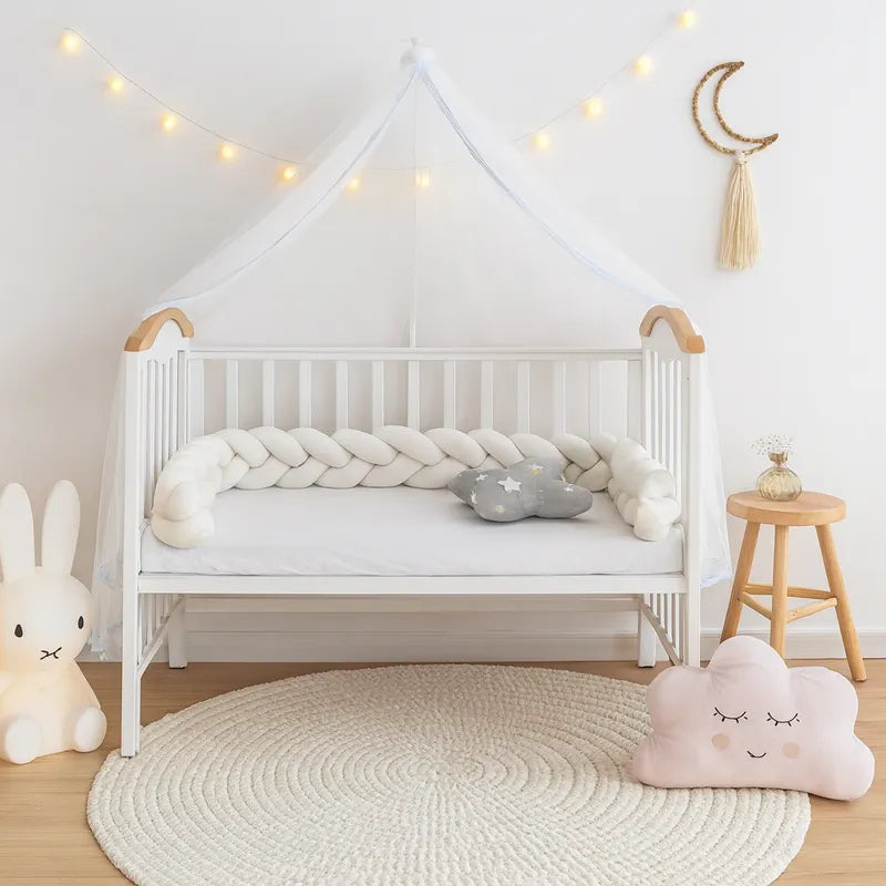 Tresse de lit bébé blanche dans un berceau décoré avec coussins 