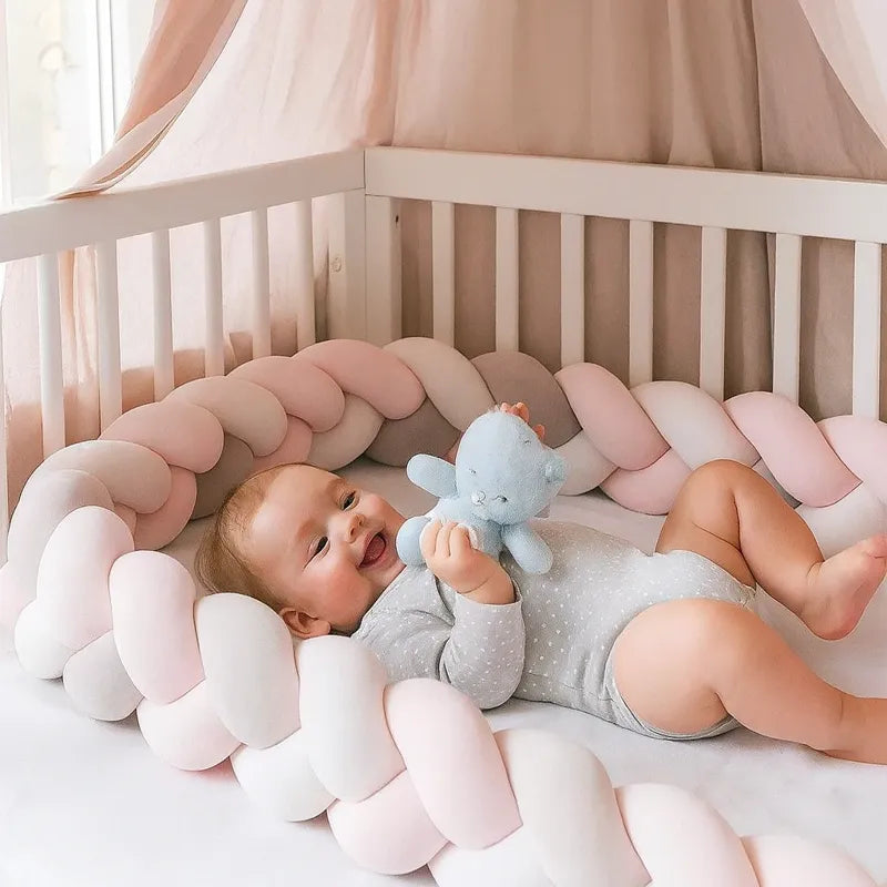 Tresse de lit bébé rose et grise avec bébé joueur tenant une peluche bleue