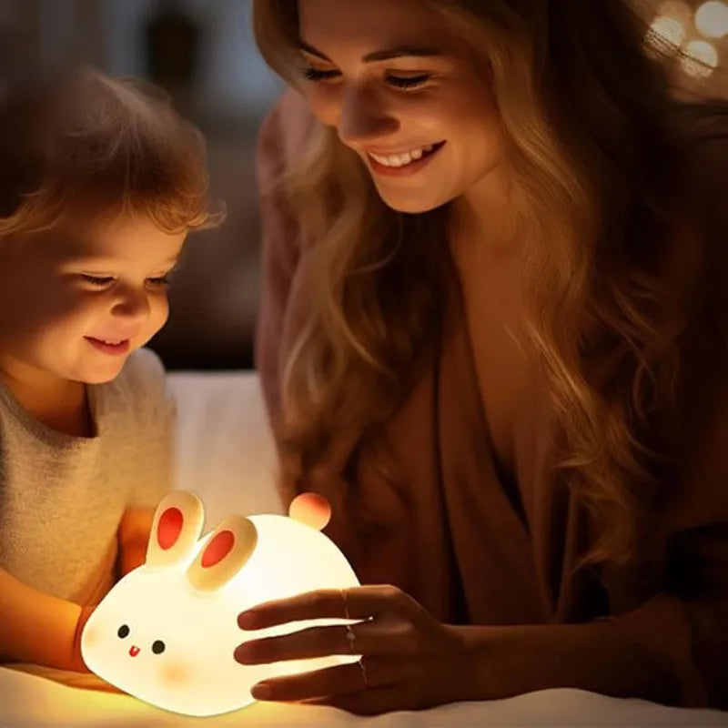 Maman et enfant souriants jouant avec une veilleuse lapin lumineuse